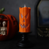Bougie LED d'Halloween orange au visage de citrouille sur bougeoir noir