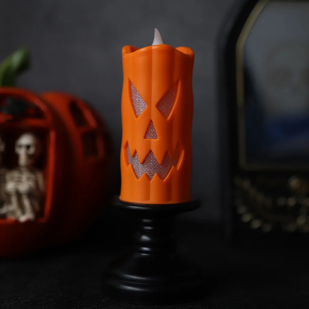 Bougie LED d'Halloween orange au visage de citrouille sur bougeoir noir